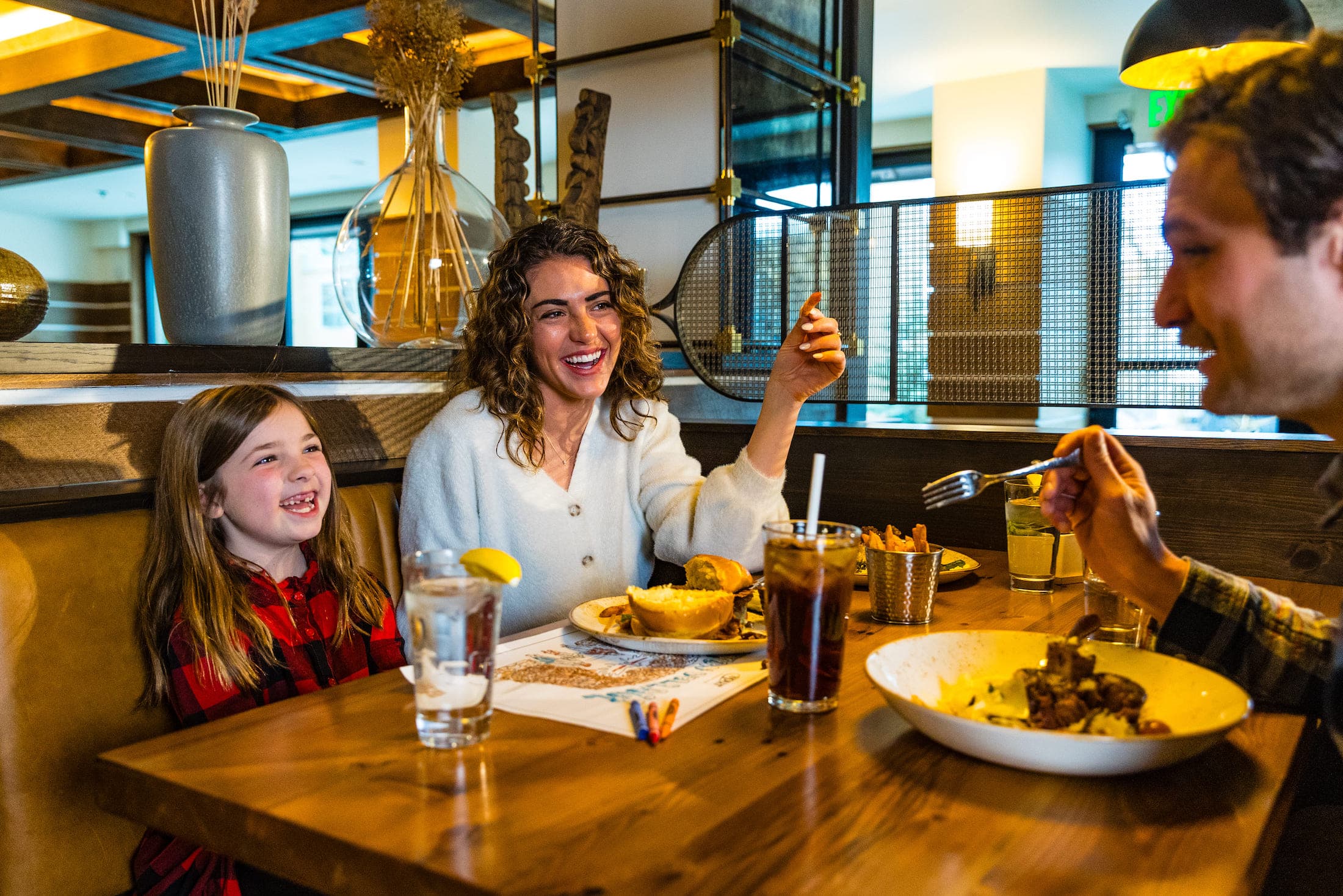 A family laughing while eating food at a restaurant at Teton Mountain Lodge