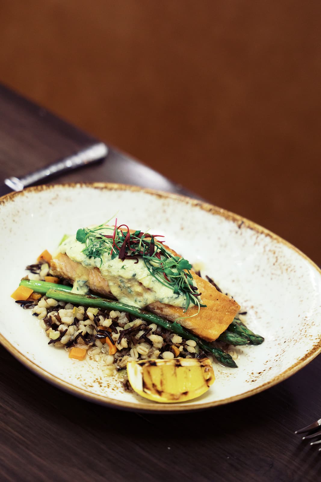 Cut of fish on top of mixed vegetables and grain.
