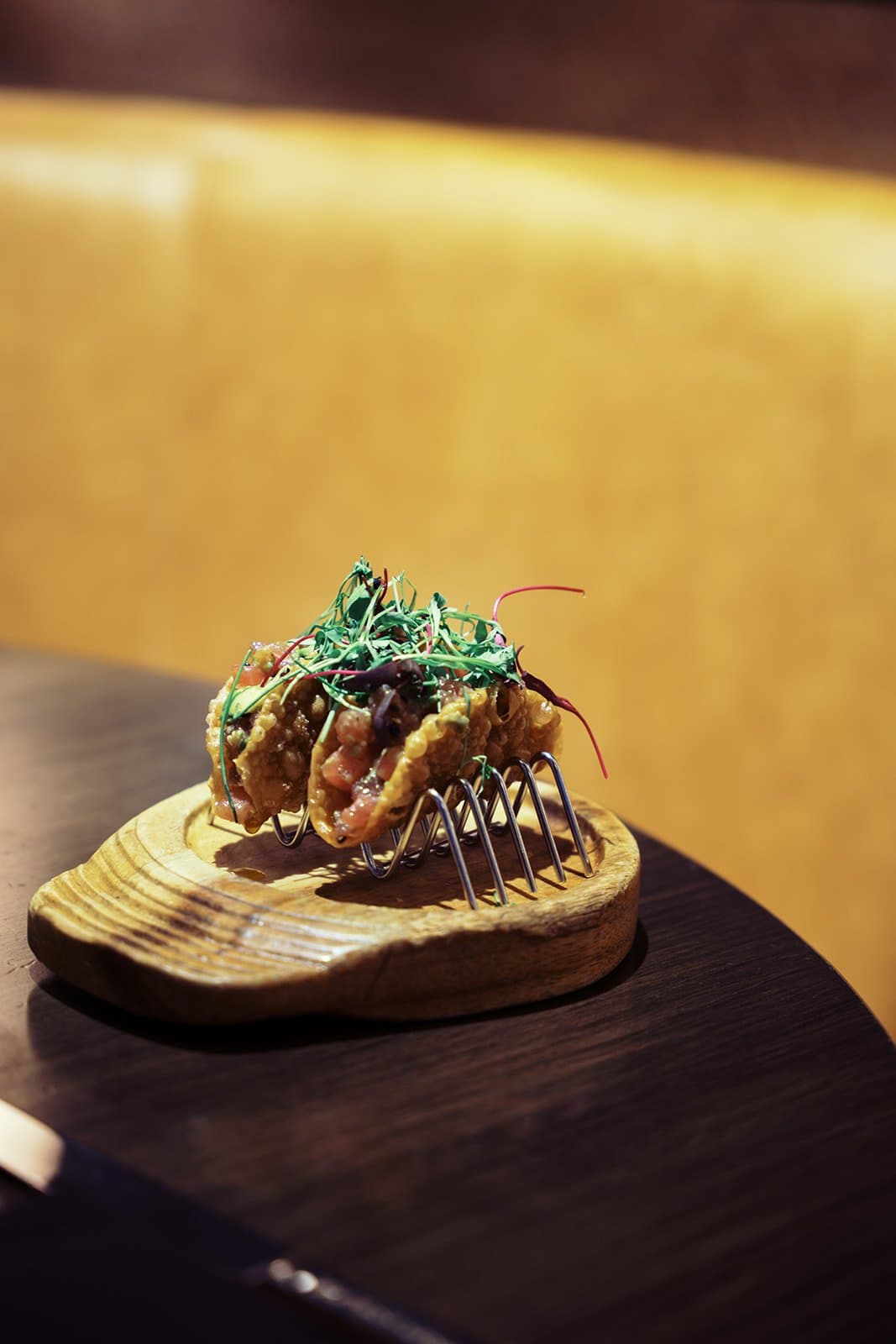Ahi Tuna in a small crispy shell taco sitting on a metal taco stand.