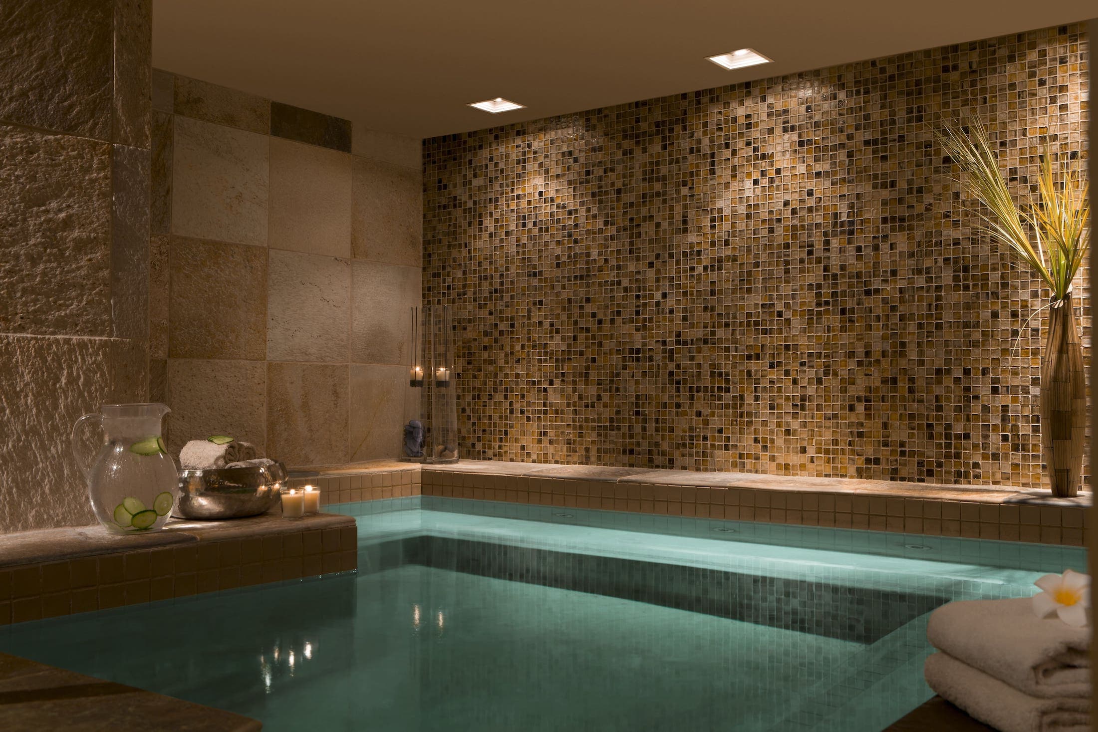 An indoor jacuzzi, with a jug of cucumber water, towels and relaxing lighting at Teton Mountain Lodge SpaTerre