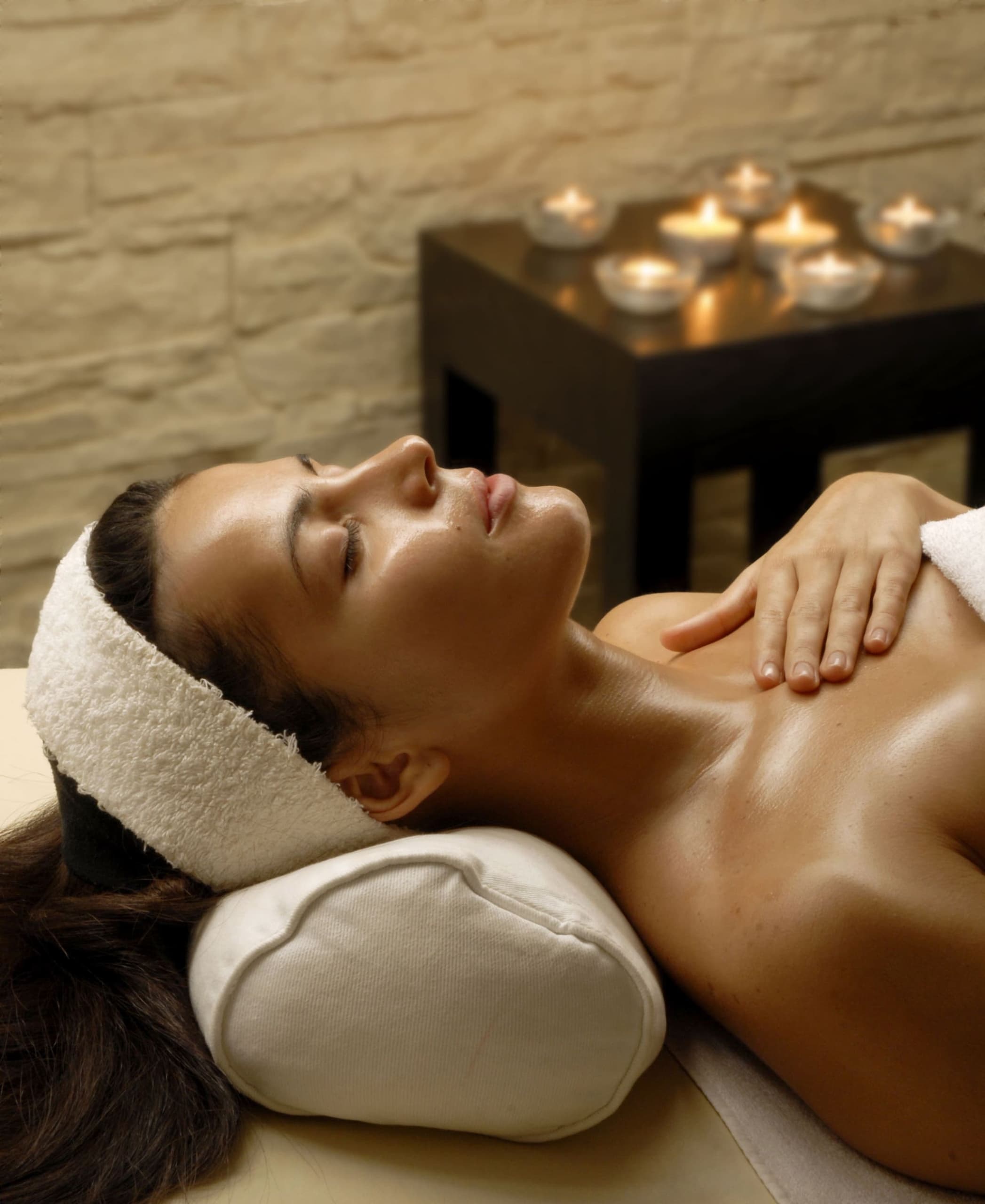 A woman laying on her back with a towel wrapped around her head and a small table with tea lights at Teton Mountain Lodge SpaTerre
