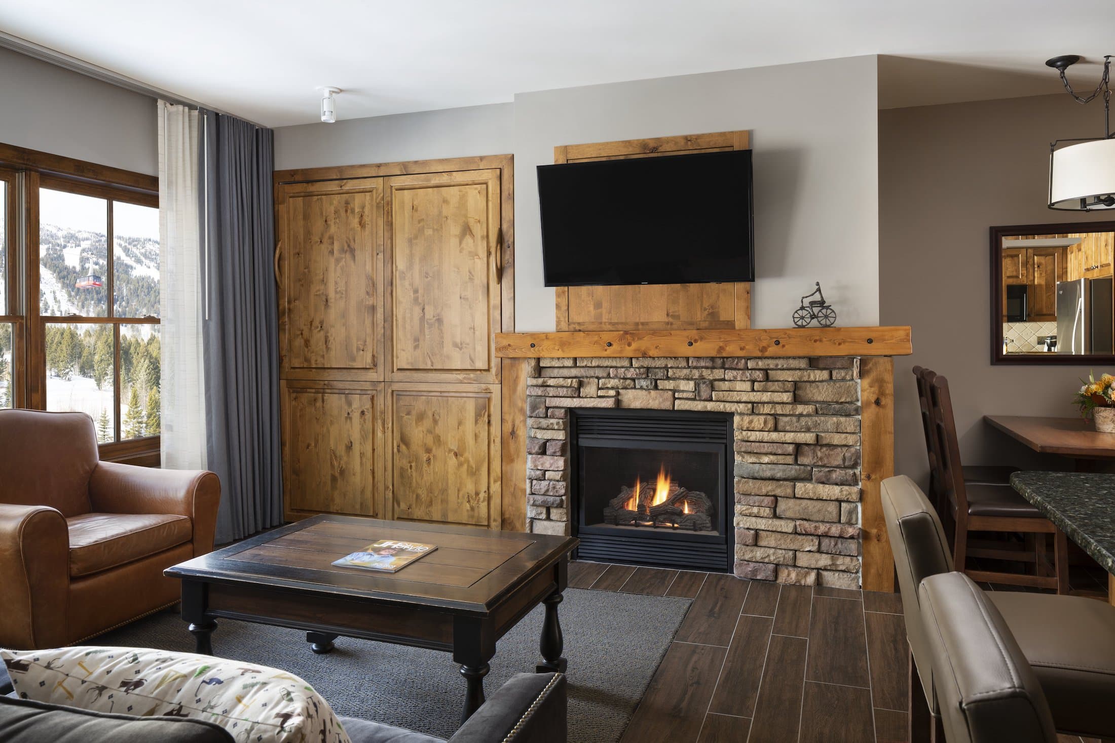 The living space with a fireplace, couch, chair, and kitchen island in the Teton Mountain Lodge Alpine Studio