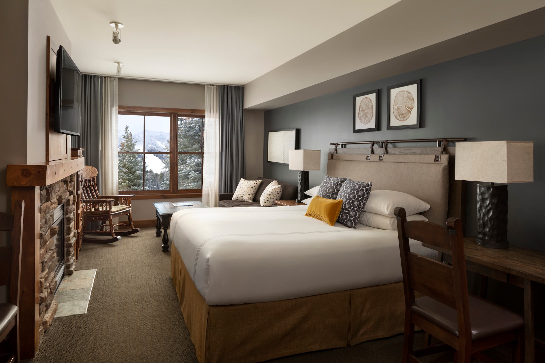 Teton Mountain Lodge Grand King room with a fireplace, Tv, desk, couch, and a beautiful view of the mountains