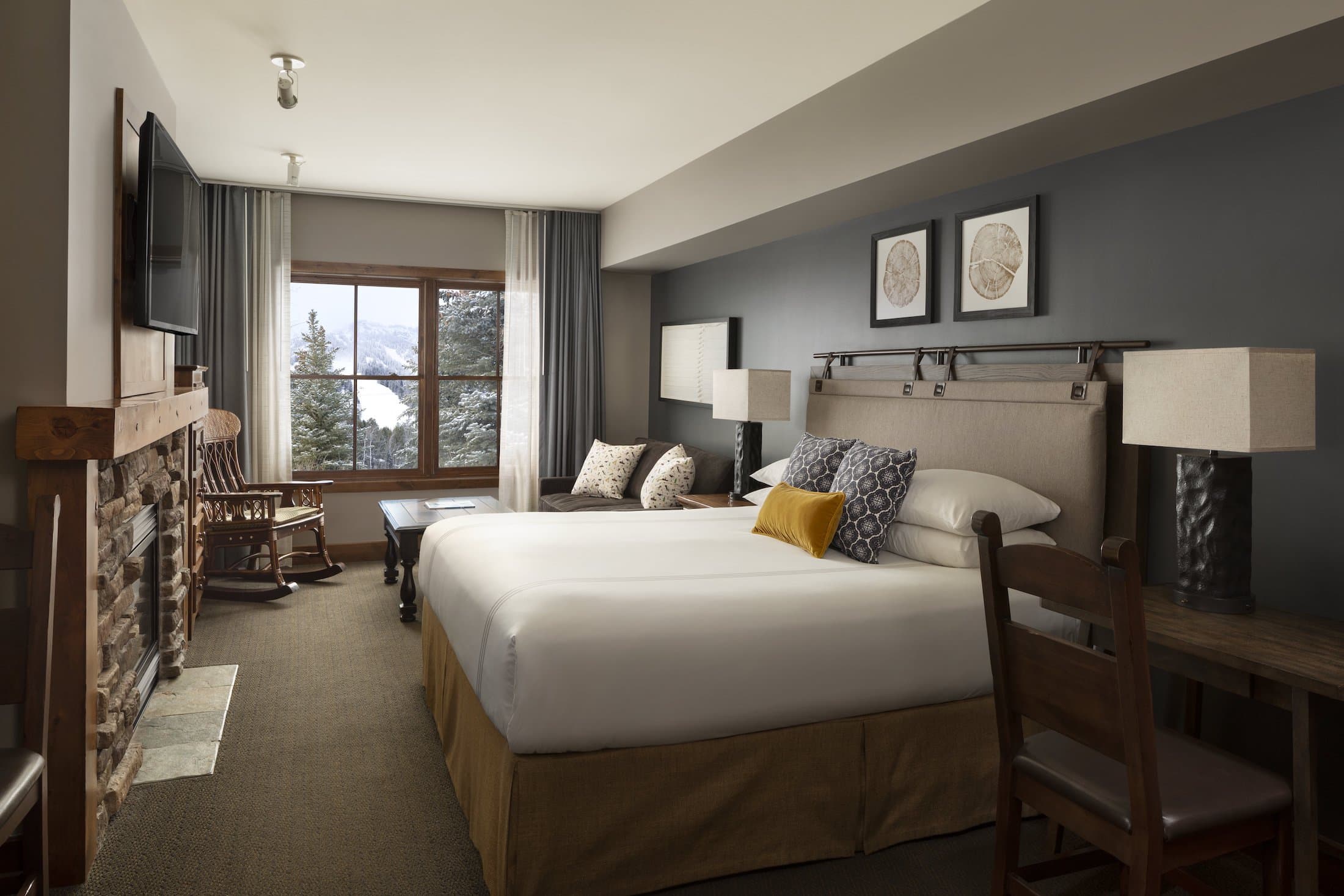 Teton Mountain Lodge Grand King room with a fireplace, Tv, desk, couch, and a beautiful view of the mountains