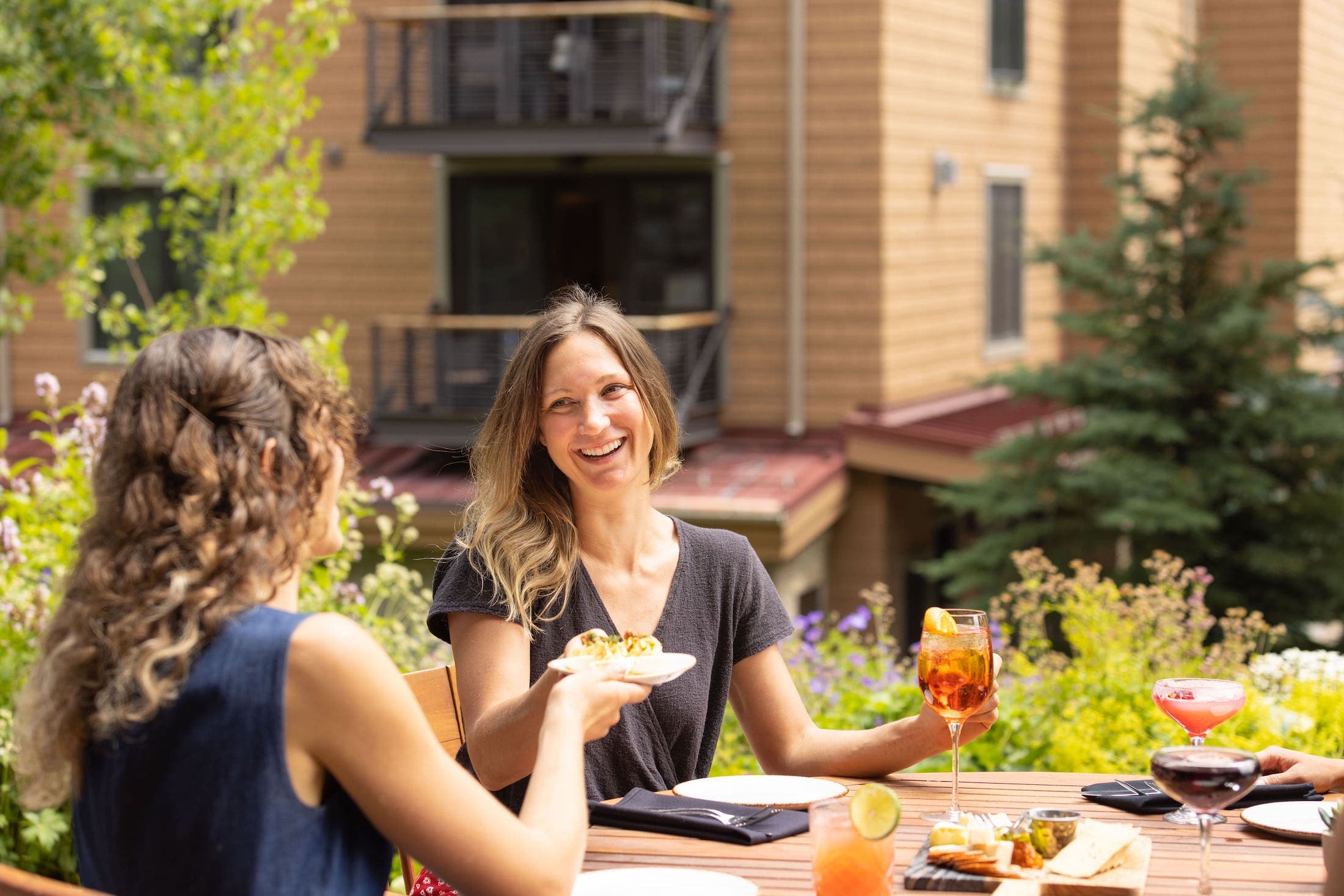 A photo of two women enjoying food and drinks outside on a summer day