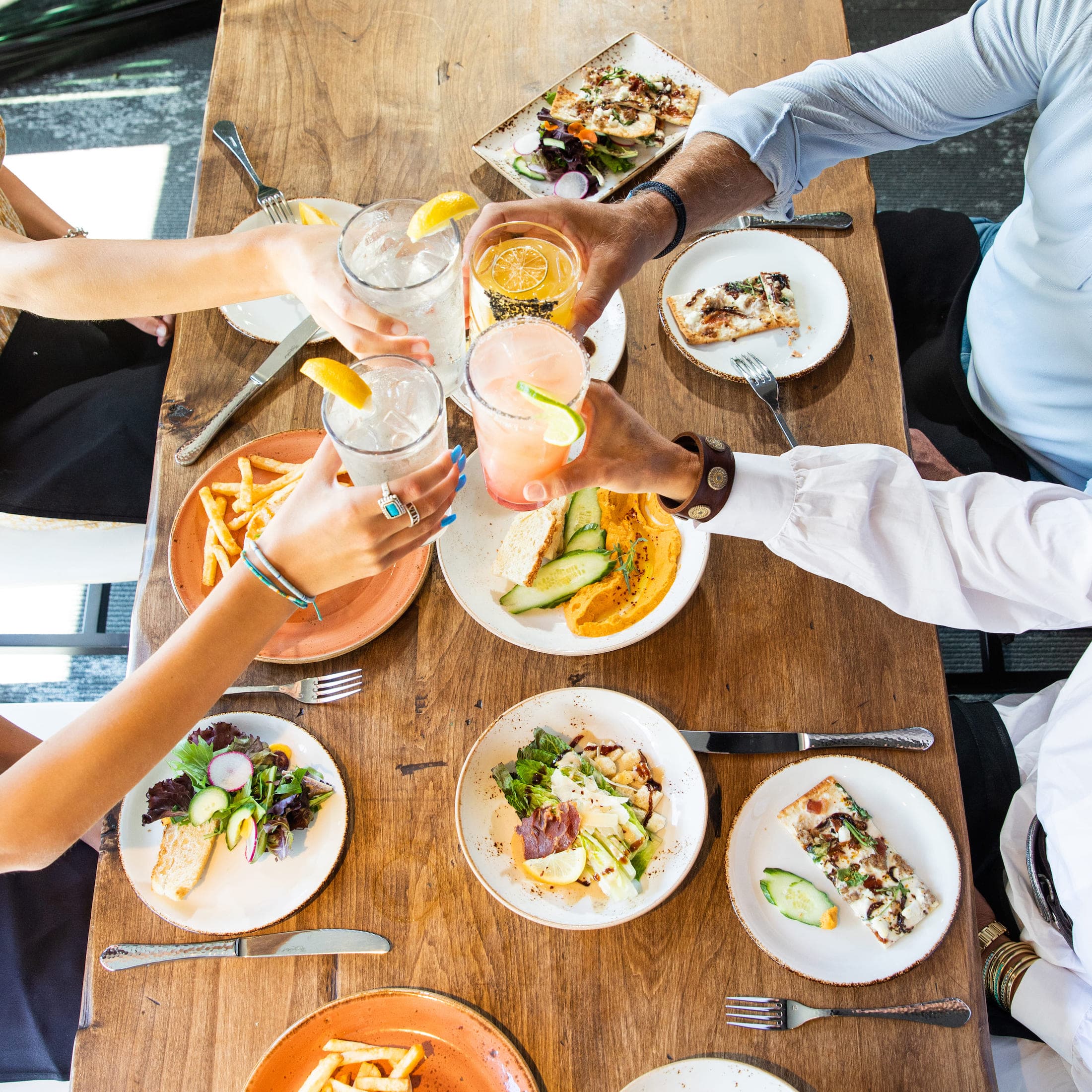 A photo of a group of four people clinking their glasses together over a table of food