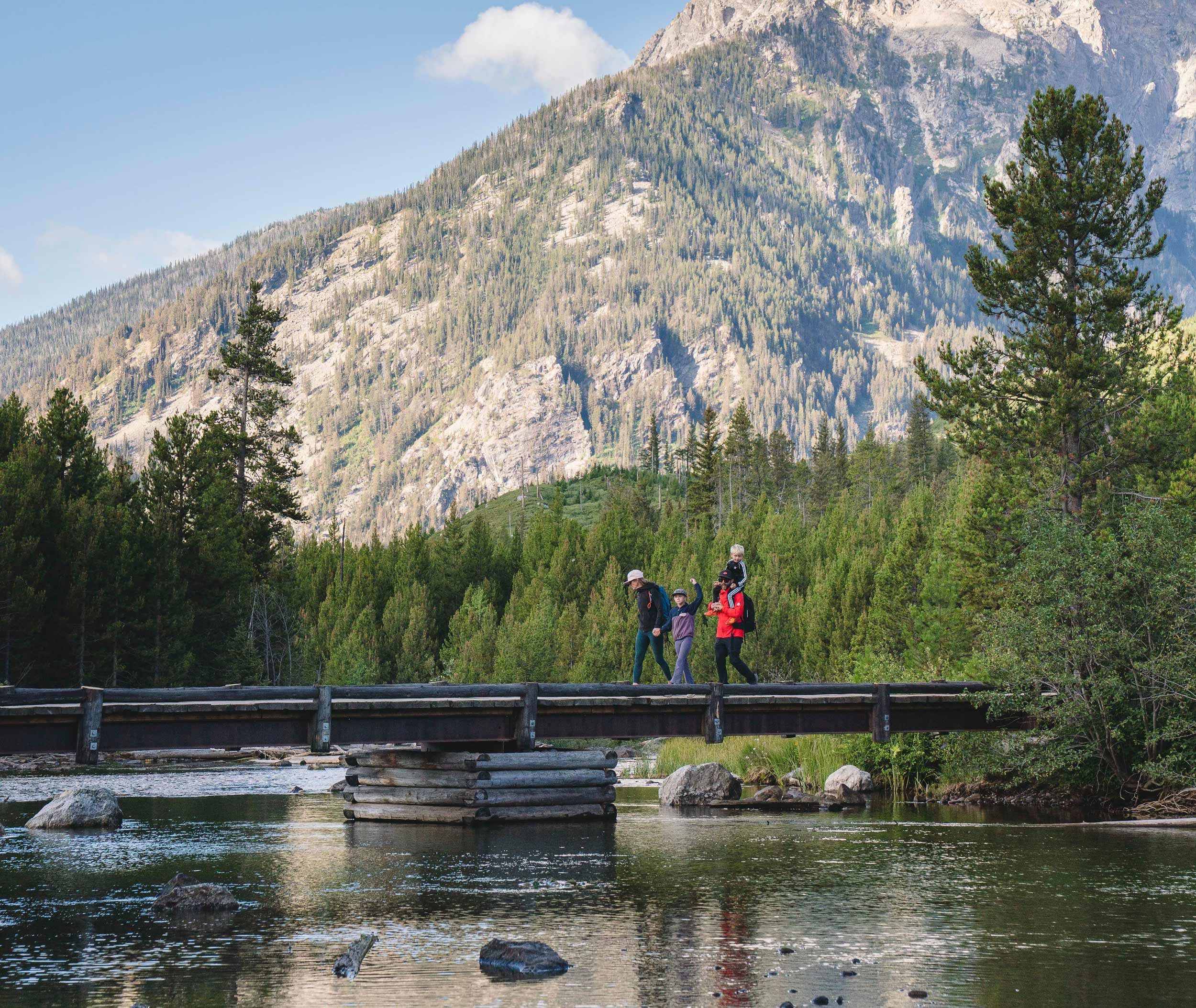 Family Walking Across A Bridge In Jackson Hole