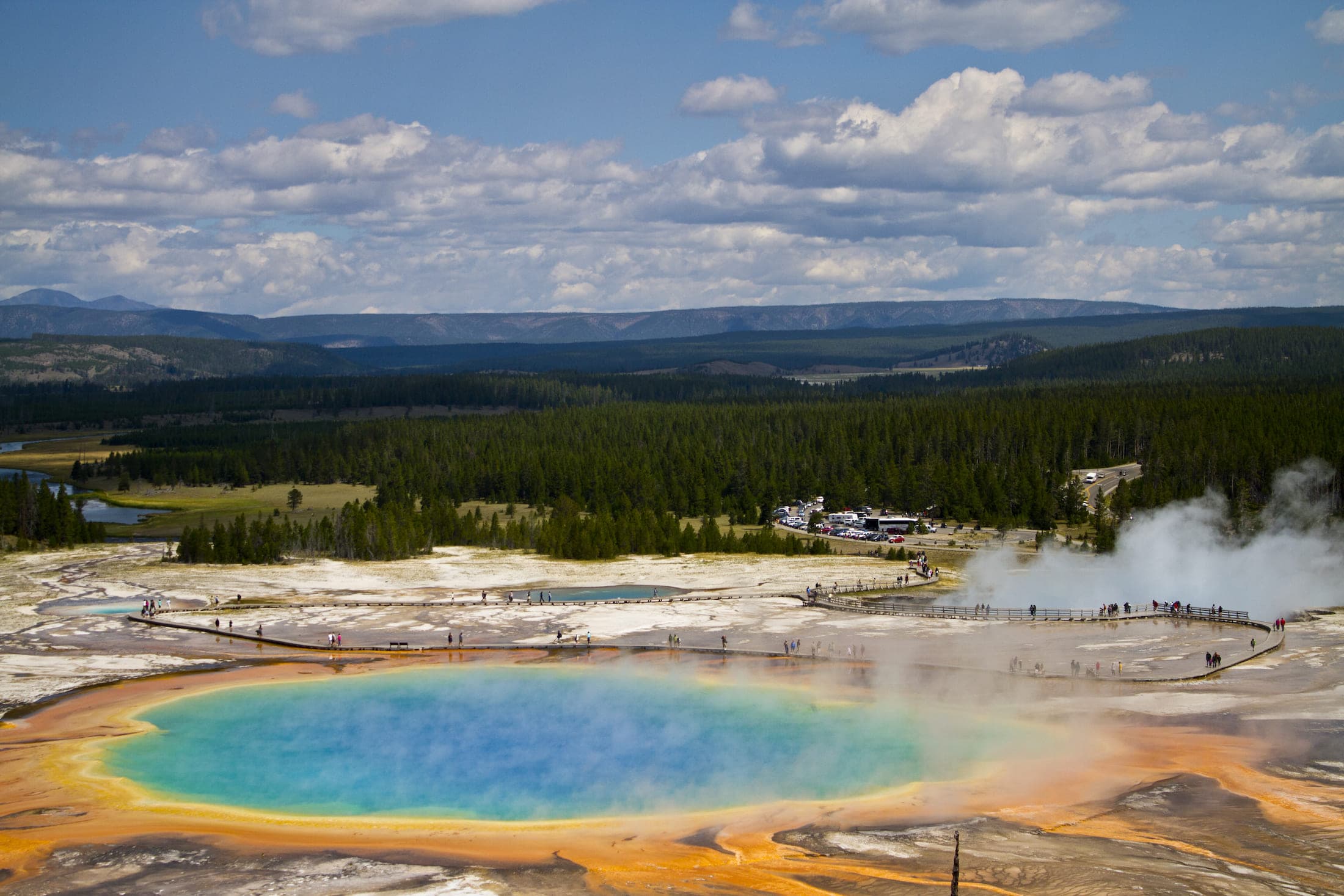 An aerial view of the Yellowstone Grand Prismatic Spring with people walking on its boardwalk