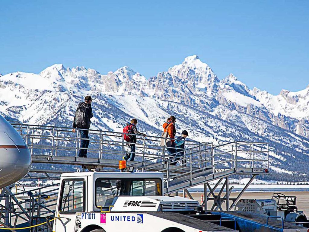 Family getting off a plane in front of the Tetons.